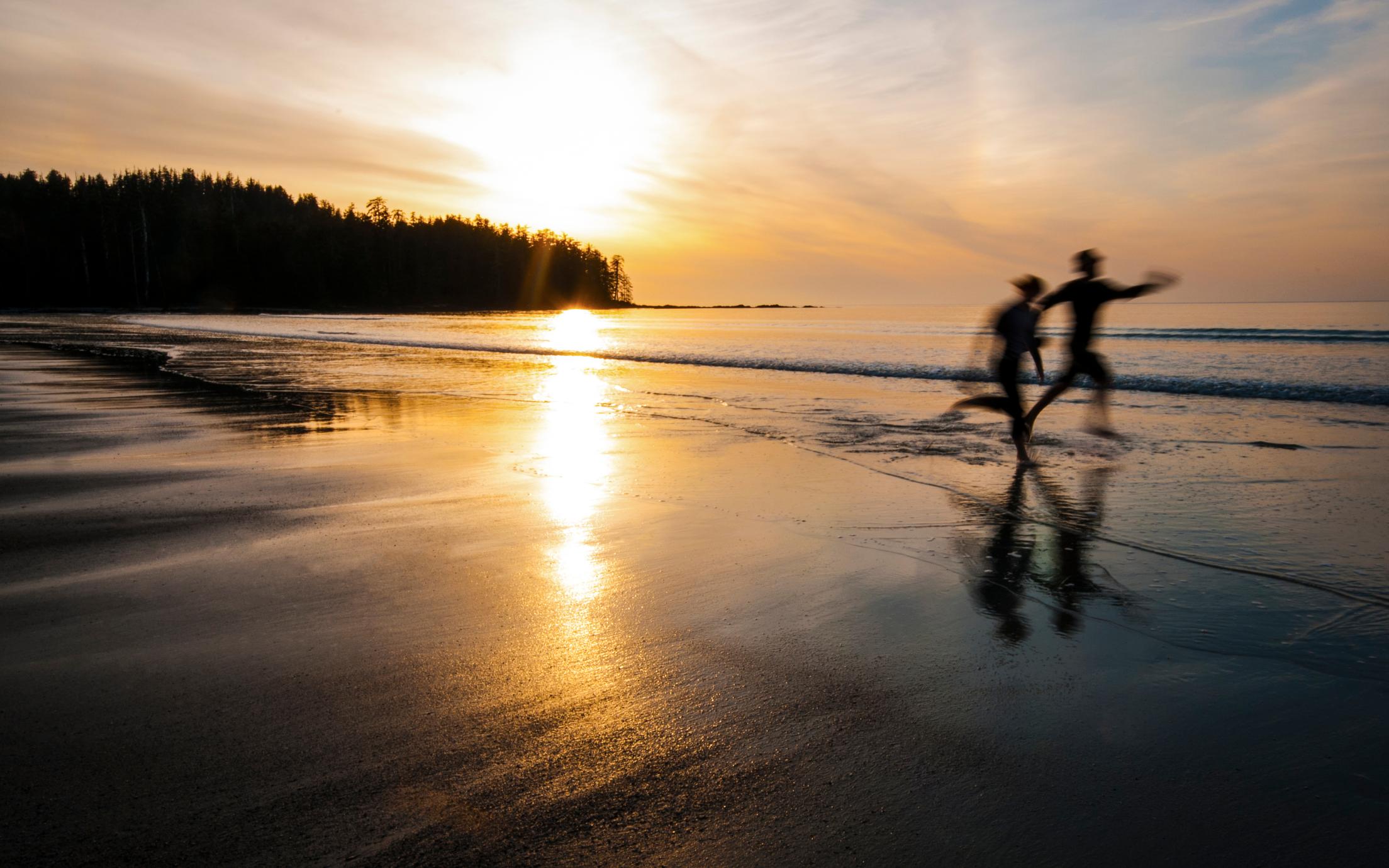couple running on ocean beach at sunset
